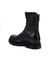 The Bed|Stü Tempt is a black leather lace-up combat boot featuring a side zipper and chunky treaded sole, blending classic combat style with rugged hiking boot elements; it’s displayed at a slight angle against a plain white background.
