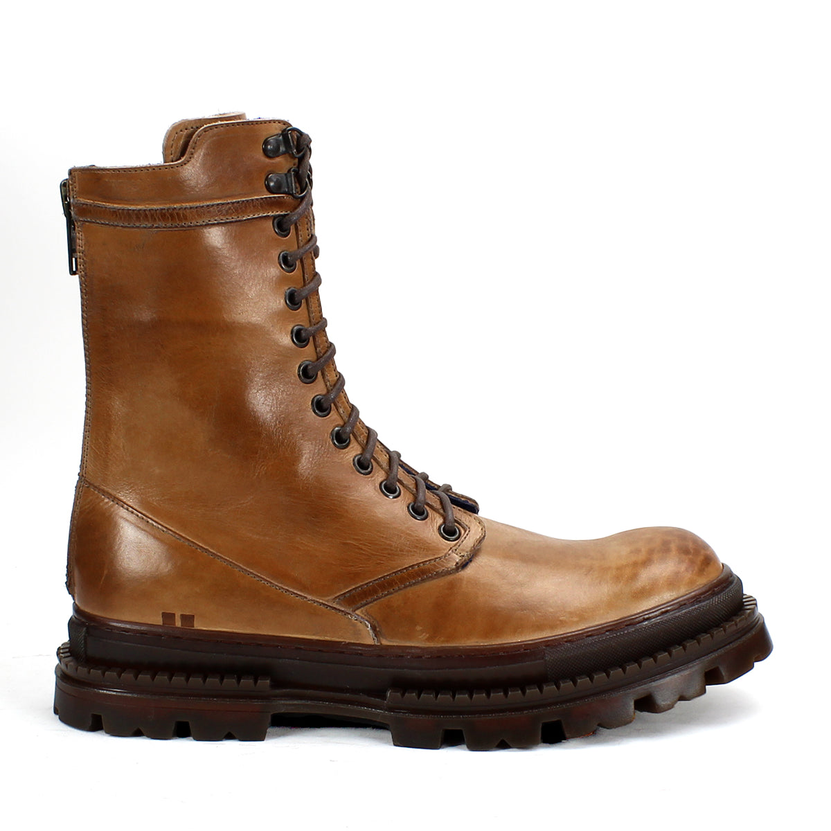 Bed|Stü's Tempt boot is a tan leather lace-up combat style featuring metal eyelets, a side zipper, and a thick, rugged dark brown sole—a stylish hybrid that fuses classic combat utility with the refined silhouette of a Chelsea boot, presented against a white background.