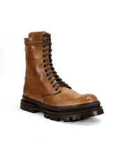 Bed|Stü's Tempt is a brown leather lace-up boot featuring a high shaft and a thick, rugged black sole. Inspired by the classic hiking boot and reimagined as a stylish hybrid, it is shown on a white background.
