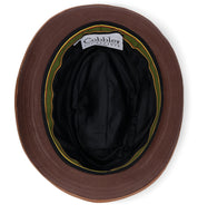 A brown bucket hat, the Turino by Bed|Stü, is shown from above, revealing a black inner lining and a label that reads "Cobbler." This crushable, lightweight design ensures everyday comfort while offering the refined look of a handmade leather hat.