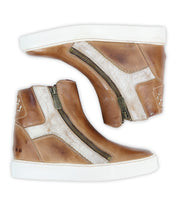 Two brown high top sneakers, the "Twist" by Bed|Stü, crafted with leather panels and featuring white accents, side zippers, and white rubber soles, are displayed side by side against a white background.