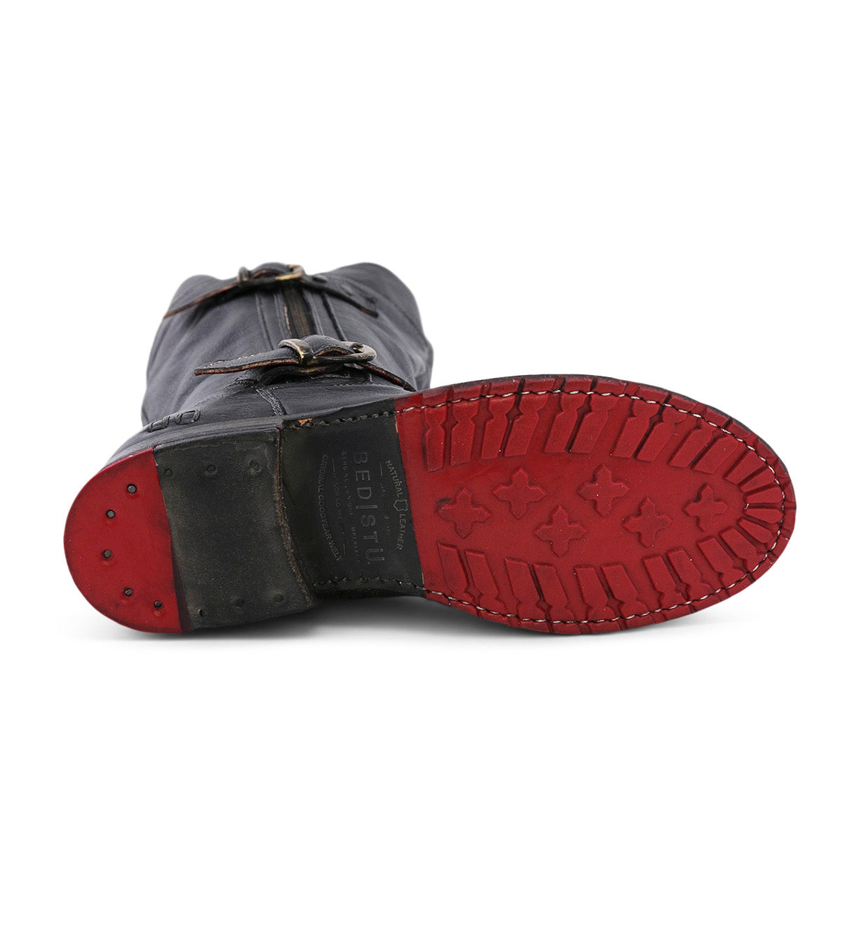 The Bed|Stü Gogo Lug Wide Calf boot is displayed sole-up, highlighting its black leather construction, red rubber tread, metal-studded heel, and visible buckles with stitching details for a rugged look.