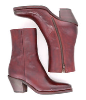 Vendue mid-heel ankle boots by Bed|Stü, crafted from reddish-brown Italian leather with avant-garde design details and side zippers, shown from side and bottom views on a white background.