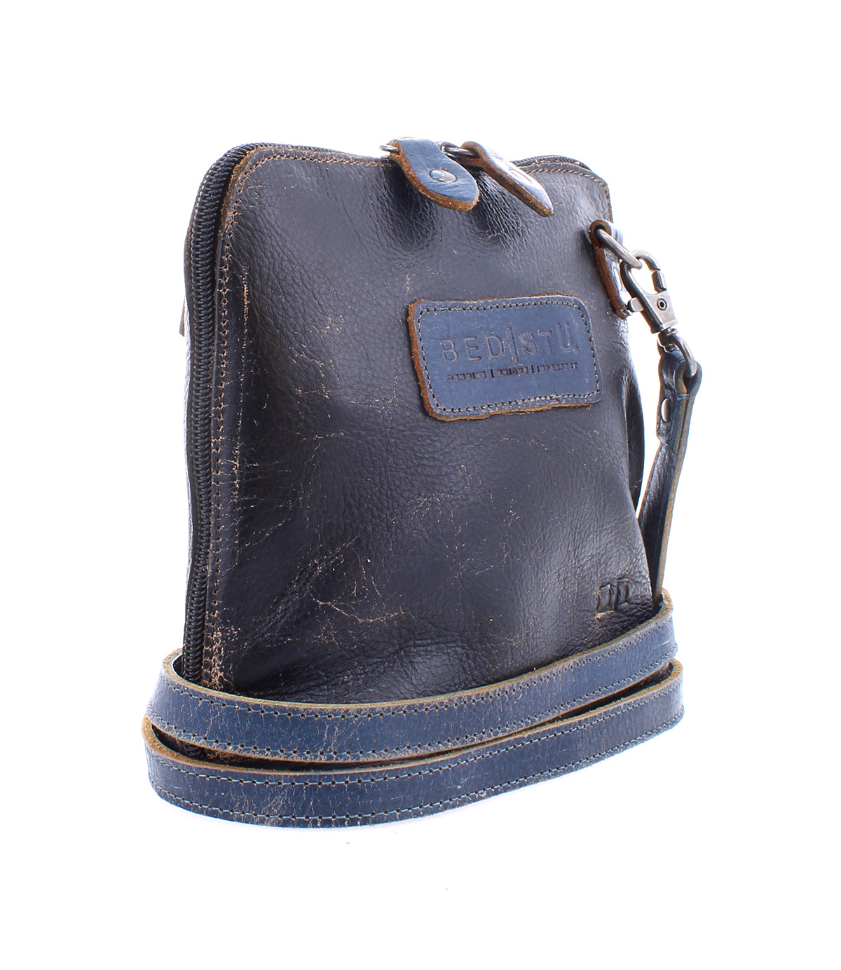 The Bed|Stü Ventura is a small, dark brown leather crossbody bag showcasing visible stitching, a metal zipper, and a long adjustable strap. An exterior zip pocket adds extra convenience to this lightweight purse, which is pictured against a white background.