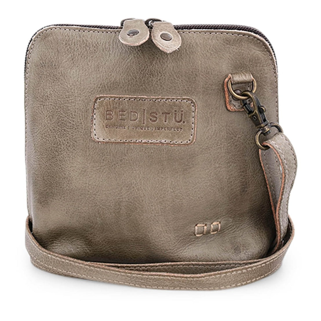 The Ventura by Bed|Stü is a square taupe leather crossbody bag featuring the signature Bed|Stü logo, front stitching detail, and a detachable strap. This lightweight purse offers a top zipper closure with two metallic pulls and an exterior zip pocket for added convenience.