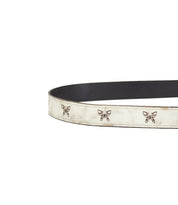 Introducing Wander by Bed|Stü: a whimsical white leather belt adorned with petite butterfly-shaped metal accents and detailed brown edging, beautifully showcased against a plain backdrop.