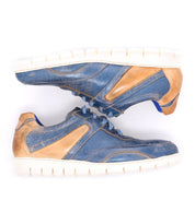 A pair of Bed|Stü Wardell blue and tan layered leather sneakers with cushioned soles, positioned side by side on a white background, offering a modern edge to classic athletic style.
