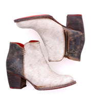 A pair of worn Yell handmade leather ankle boots by Bed|Stü, featuring side zippers, brown heels, a white distressed finish, and a durable Vibram outsole, displayed against a white background.