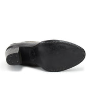 The image displays the underside of the Bed|Stü Yuno black leather dress shoe, featuring visible stitching around the sole, small metal studs on the heel, and subtle contrast leather accents that elevate its sophisticated design.