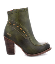 Introducing the Yuno by Bed|Stü: a green leather ankle boot featuring a chunky brown heel, decorative stitching, and cut-out details near the top and side. Designed with breathable cushioning for all-day comfort, these elevated heel boots are finished with subtle contrast leather accents for added style.