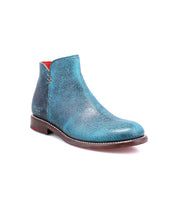 The Bed|Stü Yurisa is a single blue leather ankle boot with a textured finish, featuring a red interior lining, brown leather outsole, and low heel, shown against a white background.