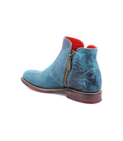 The Yurisa ankle boot by Bed|Stü features handcrafted turquoise leather, a side zipper, red interior lining, and a brown stacked heel, shown angled to the side.