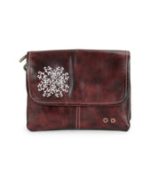 Introducing the Ziggy JB by Bed|Stü—a small brown leather crossbody bag featuring a flap closure, accented with a silver snowflake design and two metal studs on the bottom right corner. This stylish accessory is perfect for carrying your essentials while adding an elegant touch to any outfit.