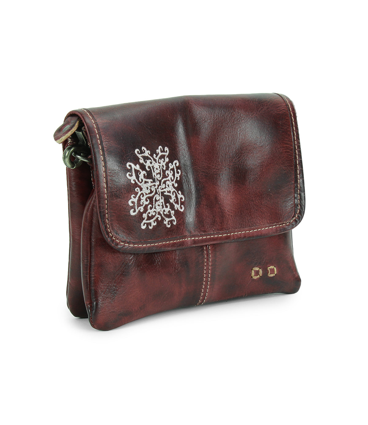The Ziggy JB by Bed|Stü is a small, dark brown leather crossbody bag with a flap closure, accented by a white embroidered design and two small metal studs on the front—ideal for those seeking the functionality of a crossbody combined with the chic appeal of a clutch.
