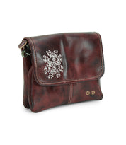 The Ziggy JB by Bed|Stü is a small, dark brown leather crossbody bag with a flap closure, accented by a white embroidered design and two small metal studs on the front—ideal for those seeking the functionality of a crossbody combined with the chic appeal of a clutch.