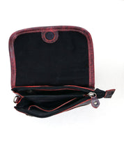 The Bed|Stü Ziggy is a small, red crossbody bag crafted from supple leather, shown with the flap open to reveal a black interior, a zippered pocket, and a button closure.